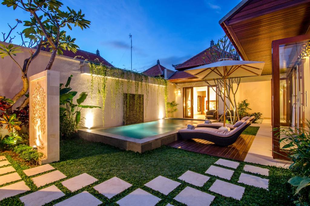 a backyard with a swimming pool and an umbrella at Kesari Haven in Sanur