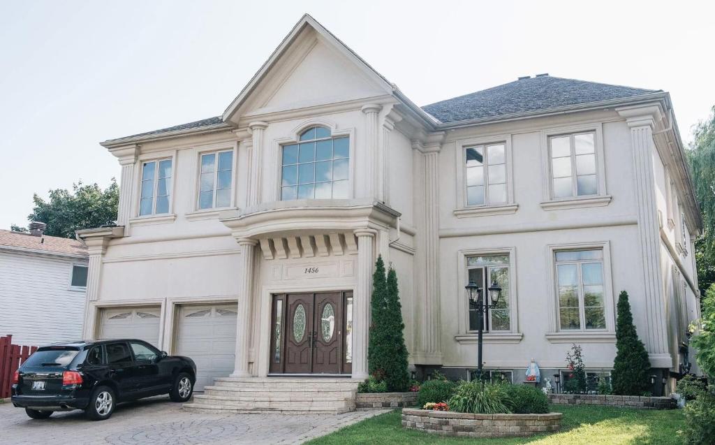 a black car parked in front of a white house at JstLikeHome - Luxury Mansion & Guesthouse in Ottawa