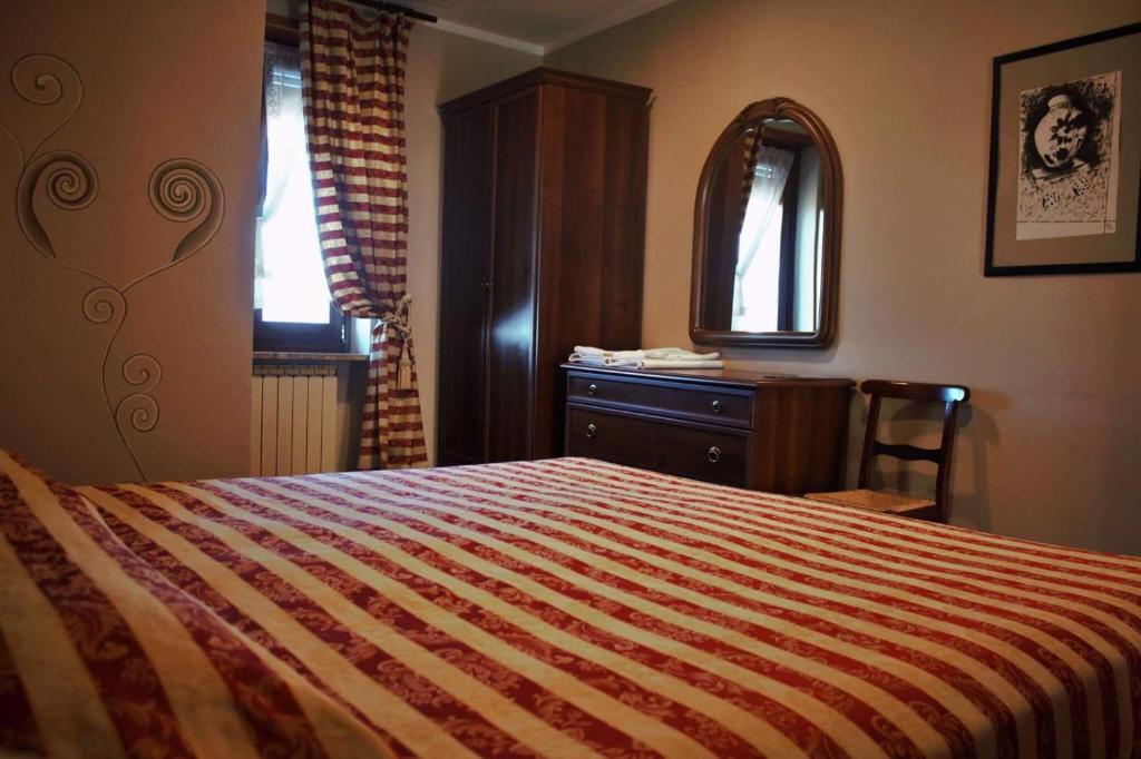a bedroom with a bed and a dresser and a mirror at Albergo Ristorante 'l Bunet in Cortemilia