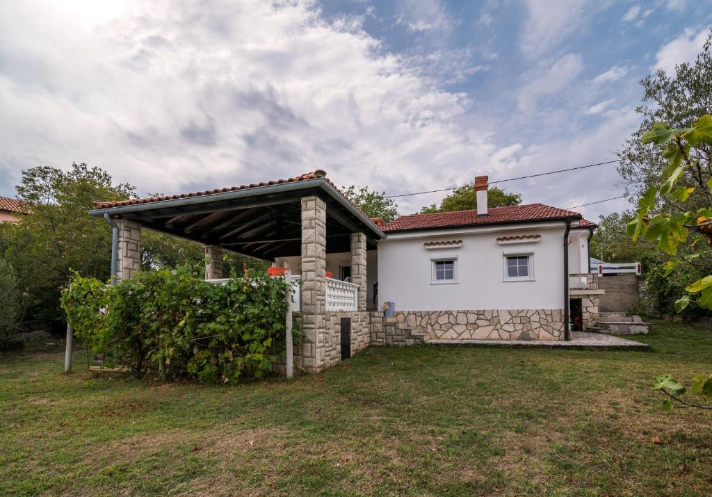 a white house with a garage in a yard at Lucy in Krk