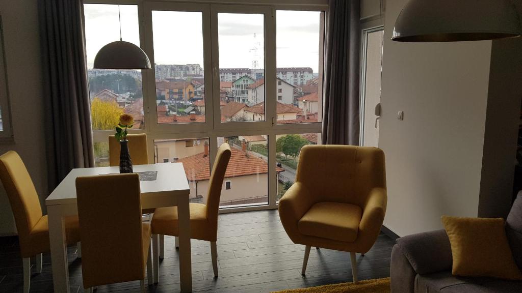 een woonkamer met een tafel en stoelen en een groot raam bij Apartman Karma in Bijeljina