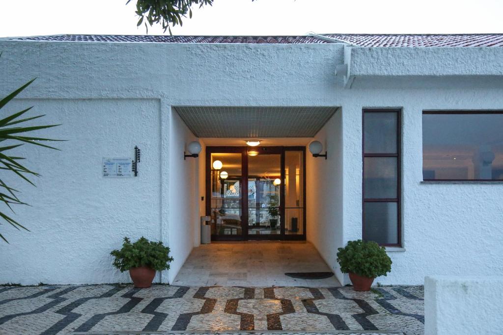 a door to a building with two potted plants at Hotel Apartamento Do Golfe in Vilamoura