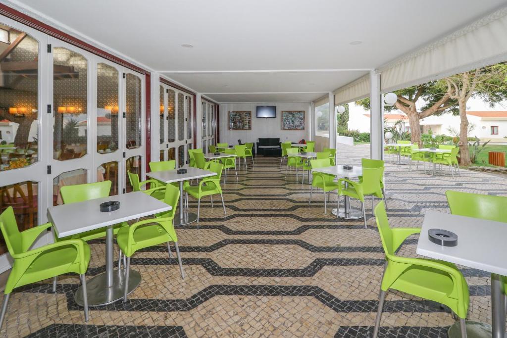 a room with tables and green chairs at Hotel Apartamento Do Golfe in Vilamoura