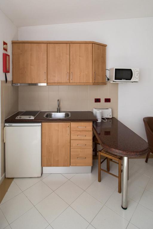 a kitchen with wooden cabinets and a table and a sink at Hotel Apartamento Do Golfe in Vilamoura
