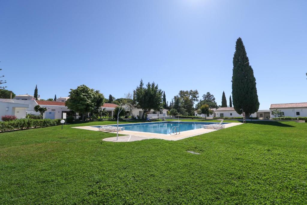 a swimming pool in a park with a grass field at Hotel Apartamento Do Golfe in Vilamoura