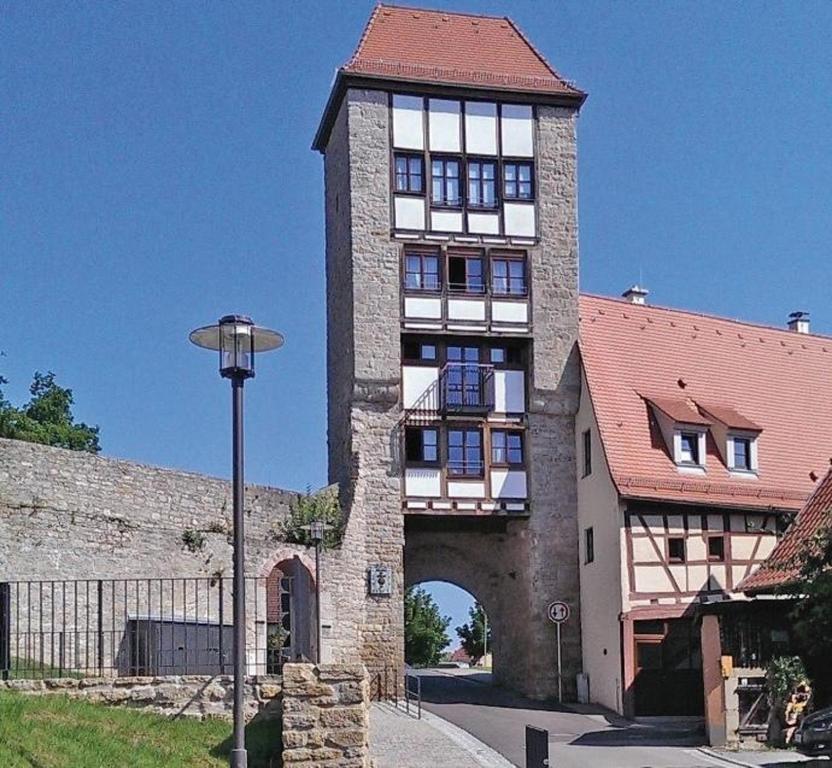 Un grand bâtiment avec une tour et une arche dans l'établissement Jakobsturm Ferien im Turm, à Röttingen