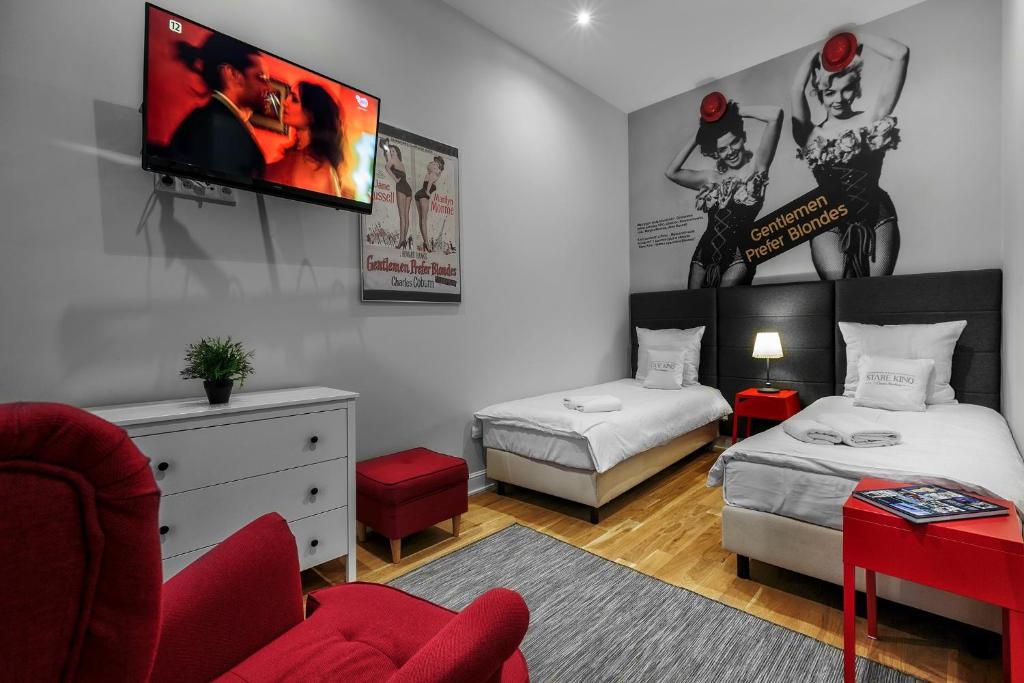 een slaapkamer met 2 bedden en een tv aan de muur bij Cinema Rooms - Piotrkowska in Łódź
