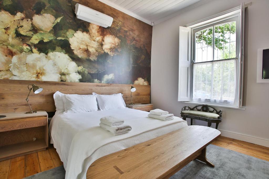a bedroom with a bed with a painting on the wall at Laanhof Victorian House Self-Catering in Stellenbosch