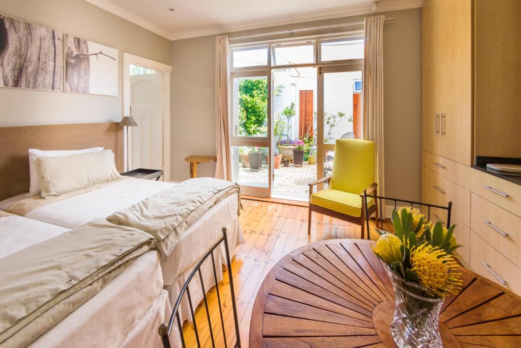 a bedroom with two beds and a table with a vase of flowers at B's Place in Port Elizabeth