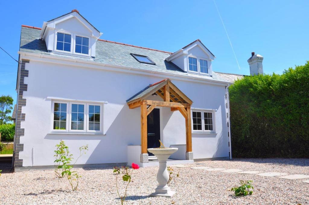 a white house with a wooden archway in front of it at Rosebank Barn in Brentor