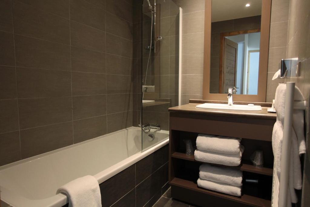 a bathroom with a bath tub and a sink and a mirror at Résidence Le Chalet du Mont Vallon in Les Menuires