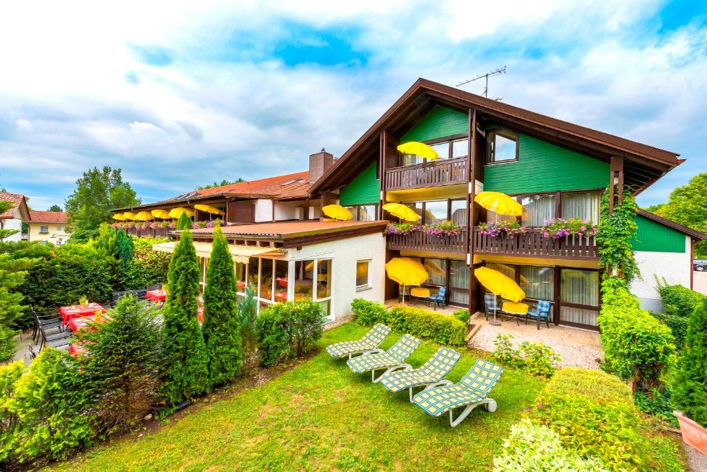 a building with chairs and umbrellas in front of it at Hotel Sonnenhof in Bad Birnbach