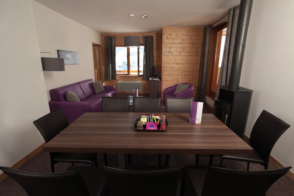 a dining room with a table and a living room at Résidence Le Chalet du Mont Vallon in Les Menuires
