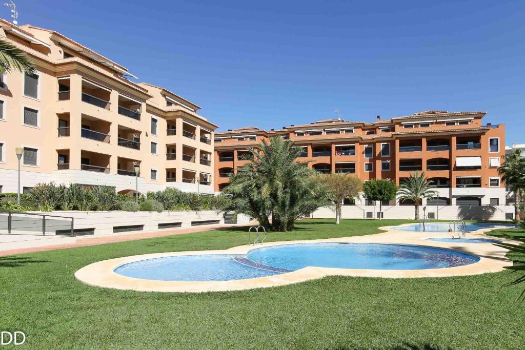 a swimming pool in the grass in front of a building at Apartment Jardines y Mar in Denia