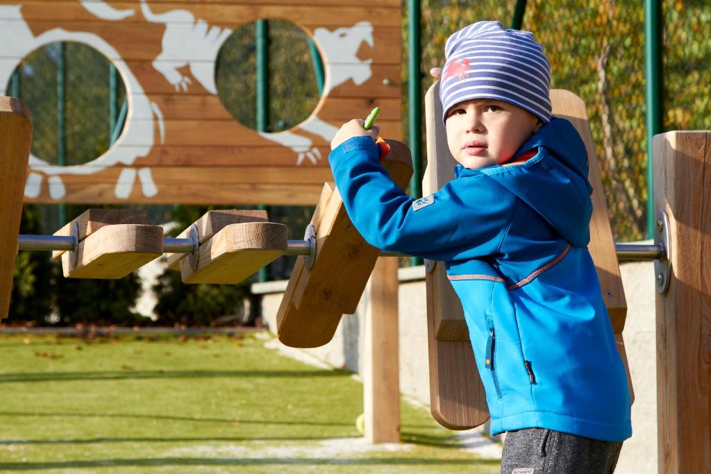 a young boy in a blue jacket playing on a playground at APARTMÁNY RYBNÍČEK in Staré Město