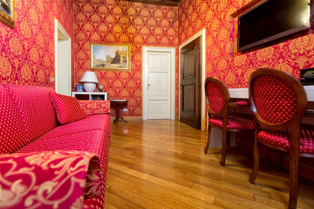 ein Wohnzimmer mit roten Wänden, einem Sofa und Stühlen in der Unterkunft Residenza Bistrot De Venise in Venedig