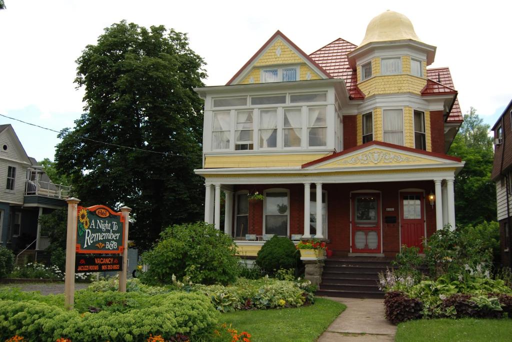 una casa amarilla y roja con un cartel delante en A Night to Remember B & B, en Niagara Falls