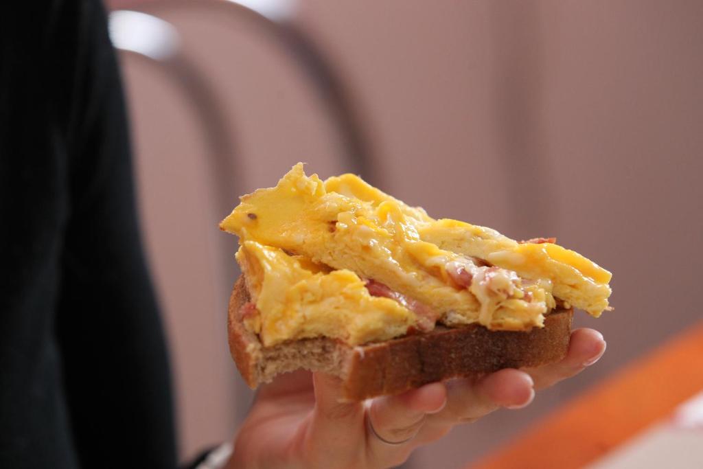 a person holding a piece of bread with cheese at Pensiunea Turistica Delmonte Holiday in Sinaia