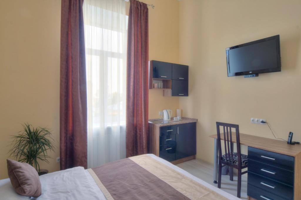 Schlafzimmer mit einem Bett, einem Schreibtisch und einem TV in der Unterkunft Best Season Apart Hotel in Kiew
