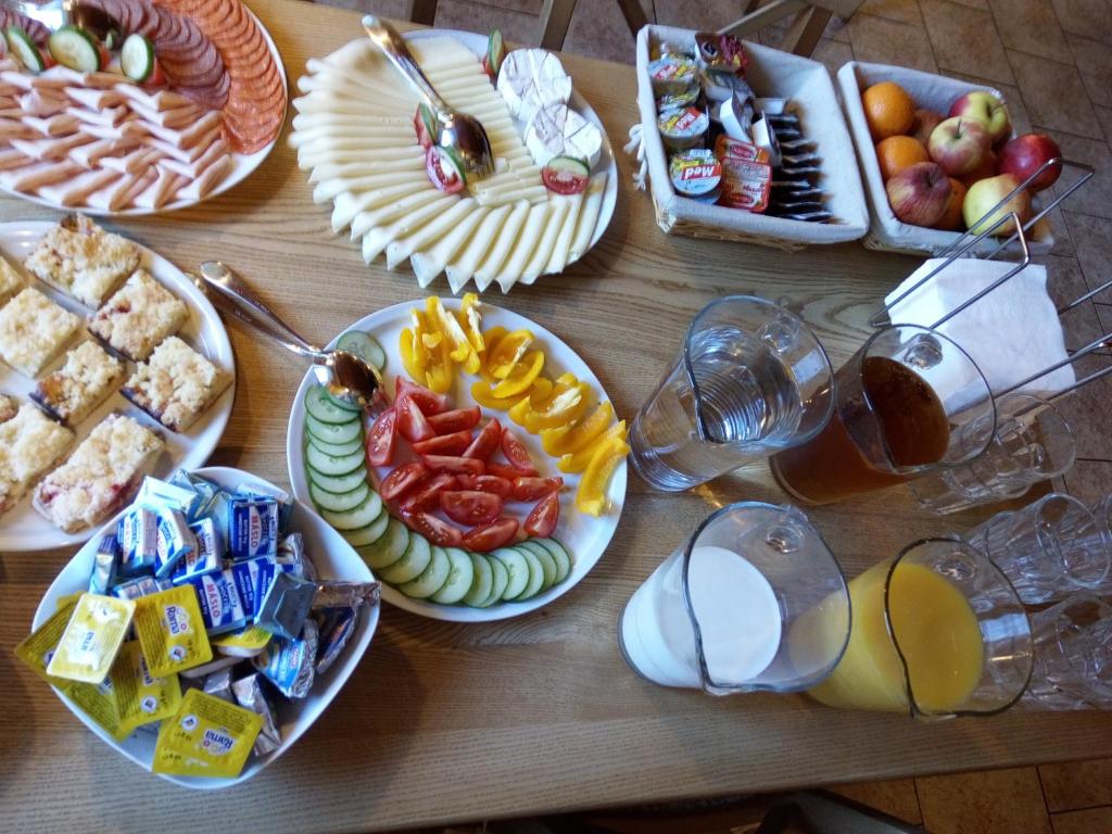 a wooden table with plates of food and drinks at Hotel Orix in Jáchymov