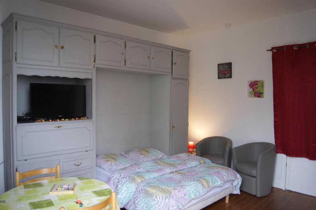 a bedroom with a bed and a dresser with a television at La Précieuse in Mers-les-Bains