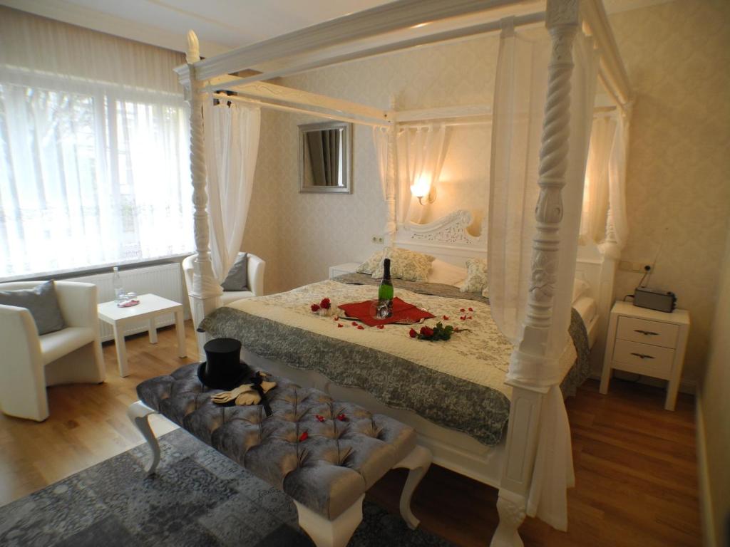 a bedroom with a four poster bed and a couch at Stadtparkhotel Alexandra in Bad Harzburg