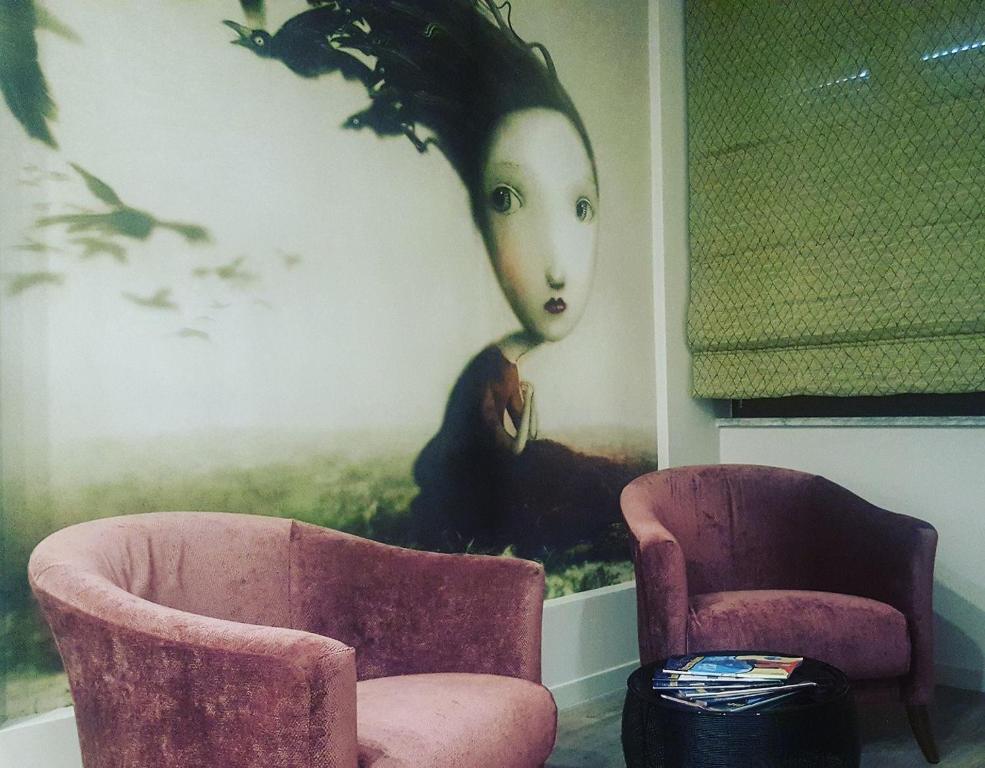 カッシーノにあるB&B Pariniの椅子2脚と女性絵画1枚付きの部屋