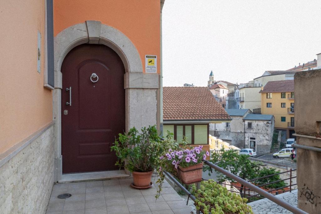 リオネーロ・イン・ヴルトゥレにあるAria di Casaの花の咲く建物の脇の茶色い扉