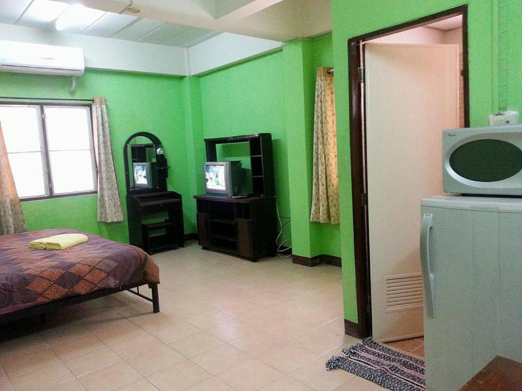 a bedroom with green walls and a bed and a tv at Roong-Arun Apartment in Bangkok