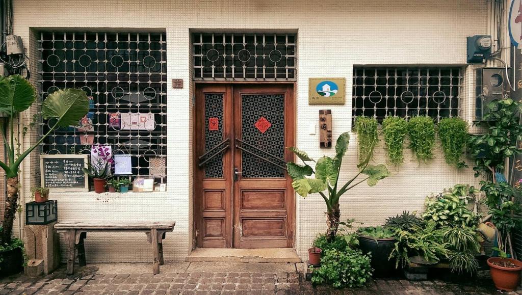 una casa con una puerta de madera y algunas plantas en Shennong 147, en Tainan