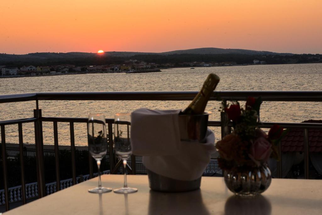 een tafel met wijnglazen op een balkon met uitzicht op de zonsondergang bij Sunset Deluxe Villa in Vir