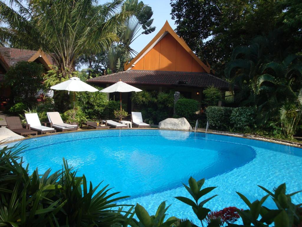 a large blue swimming pool with chairs and umbrellas at Palm Garden Resort in Rawai Beach