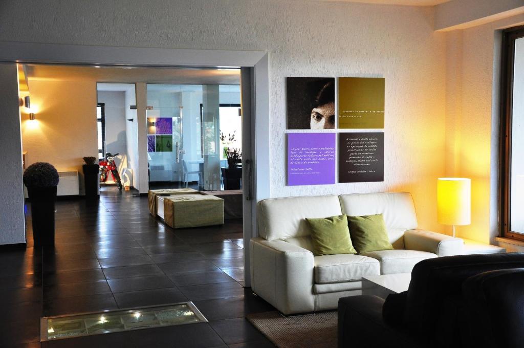 a living room with a white couch and green pillows at Hotel Sandalia in Nuoro