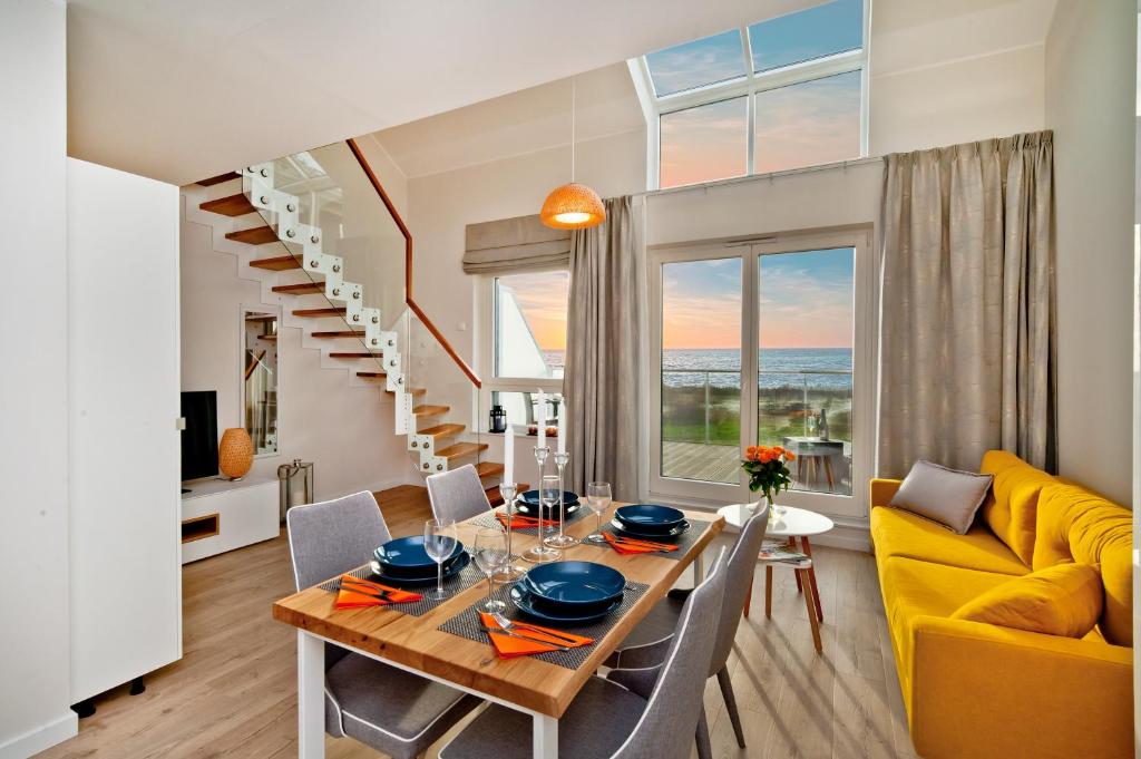 a dining room with a table and a yellow couch at BlueApart Apartamenty Na Plaży Jastarnia in Jastarnia