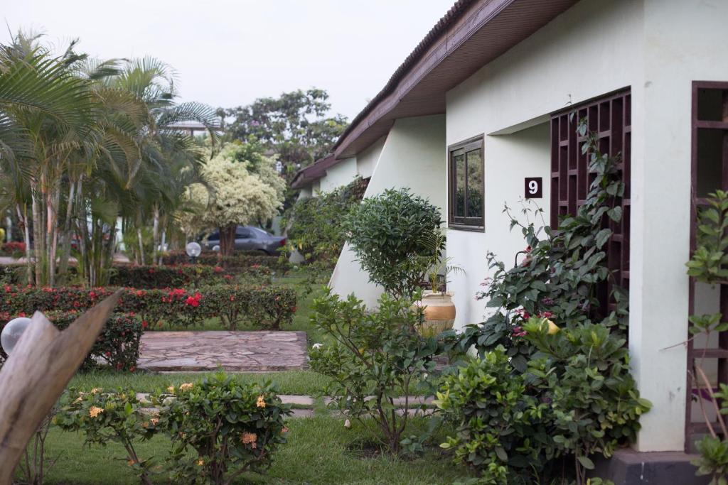 una casa blanca con un patio con flores y plantas en Travellers Palm Court, en North Legon