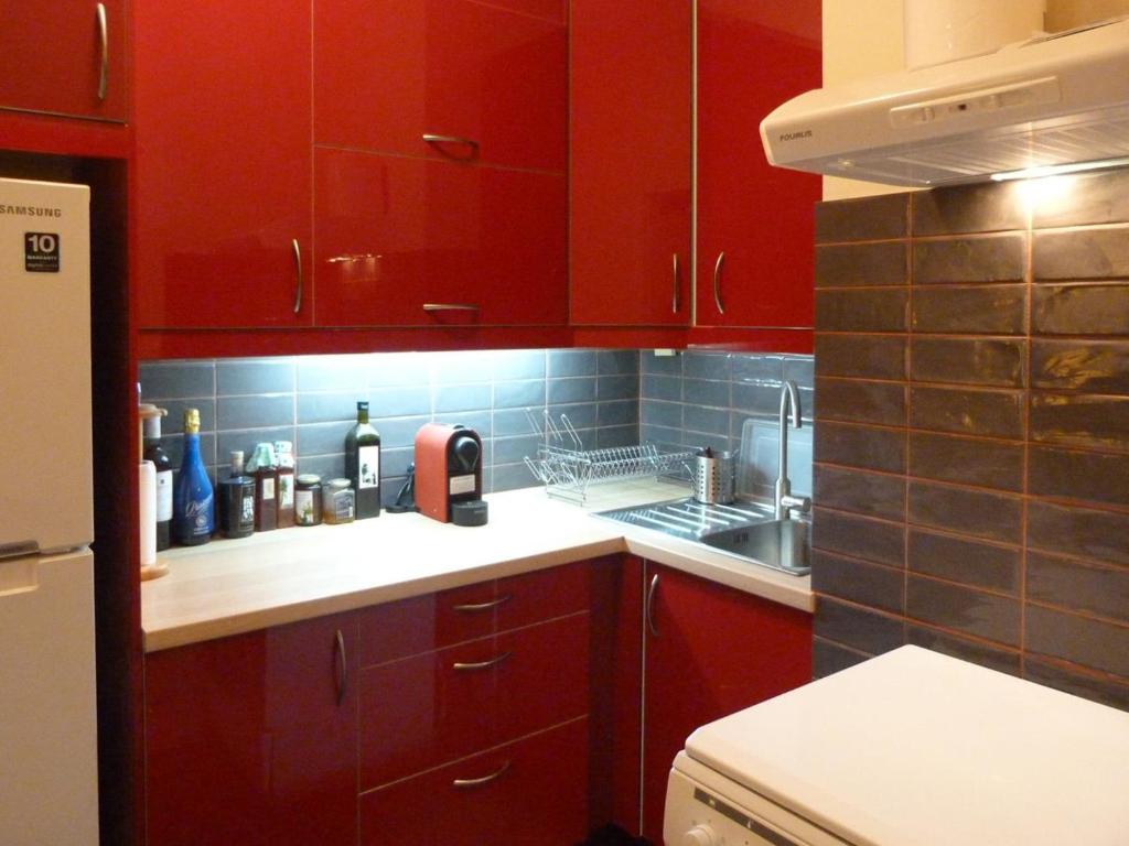a kitchen with red cabinets and a sink and a stove at Homely Spacious Studio in Chalkida