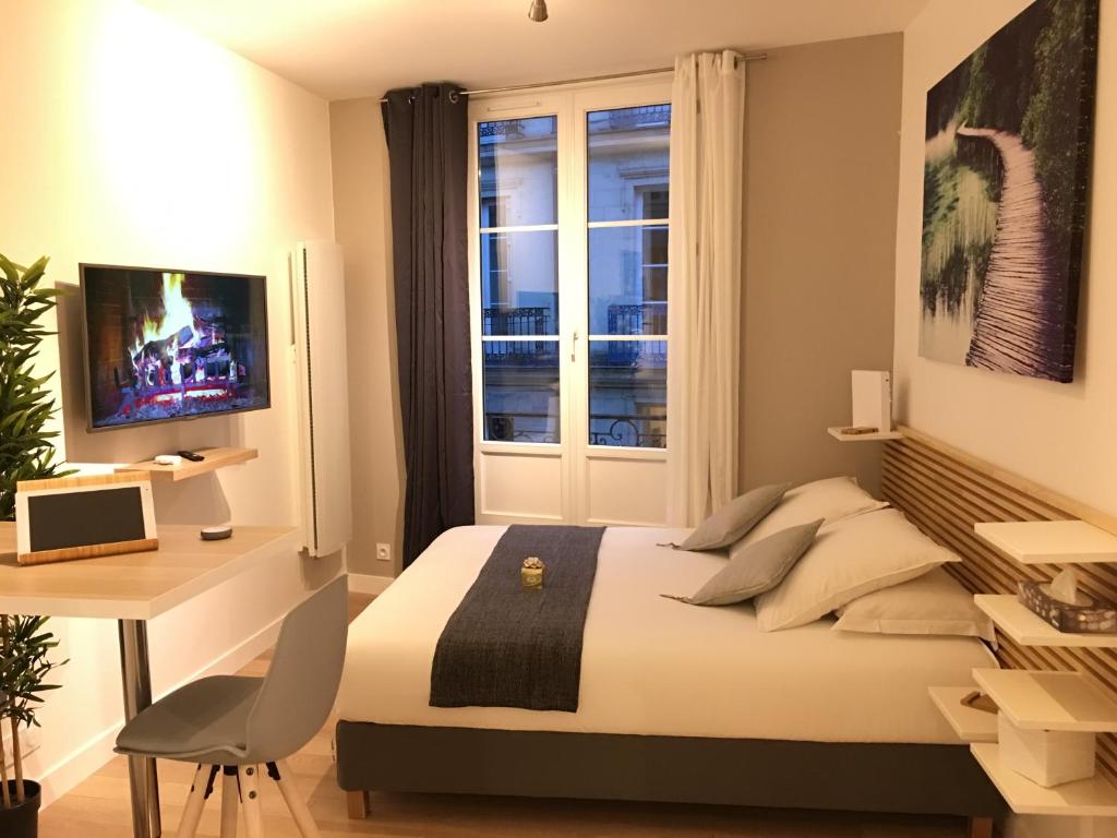 1 dormitorio con cama, escritorio y ventana en LOCKIA APPART-HÔTELS AUTOMATIQUES - Nantes Centre, en Nantes