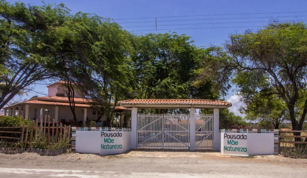 a gate in front of a house with trees at Pousada Mae Natureza in Icapuí