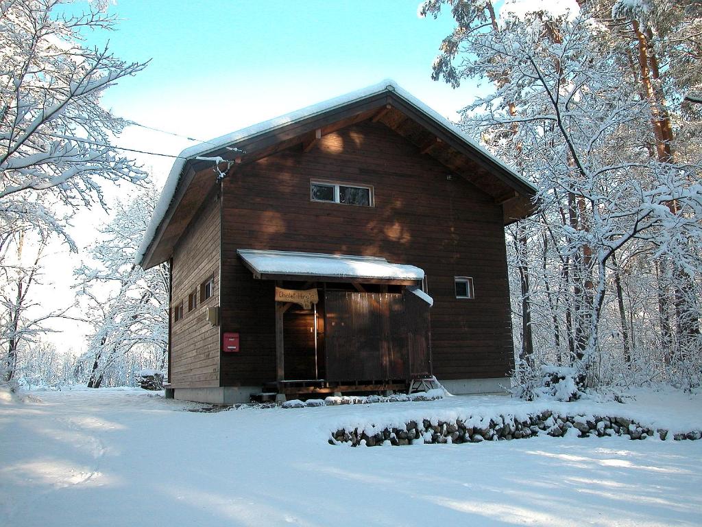 Cabaña de madera en la nieve con árboles nevados en Chalet Hinata Hakuba, en Hakuba