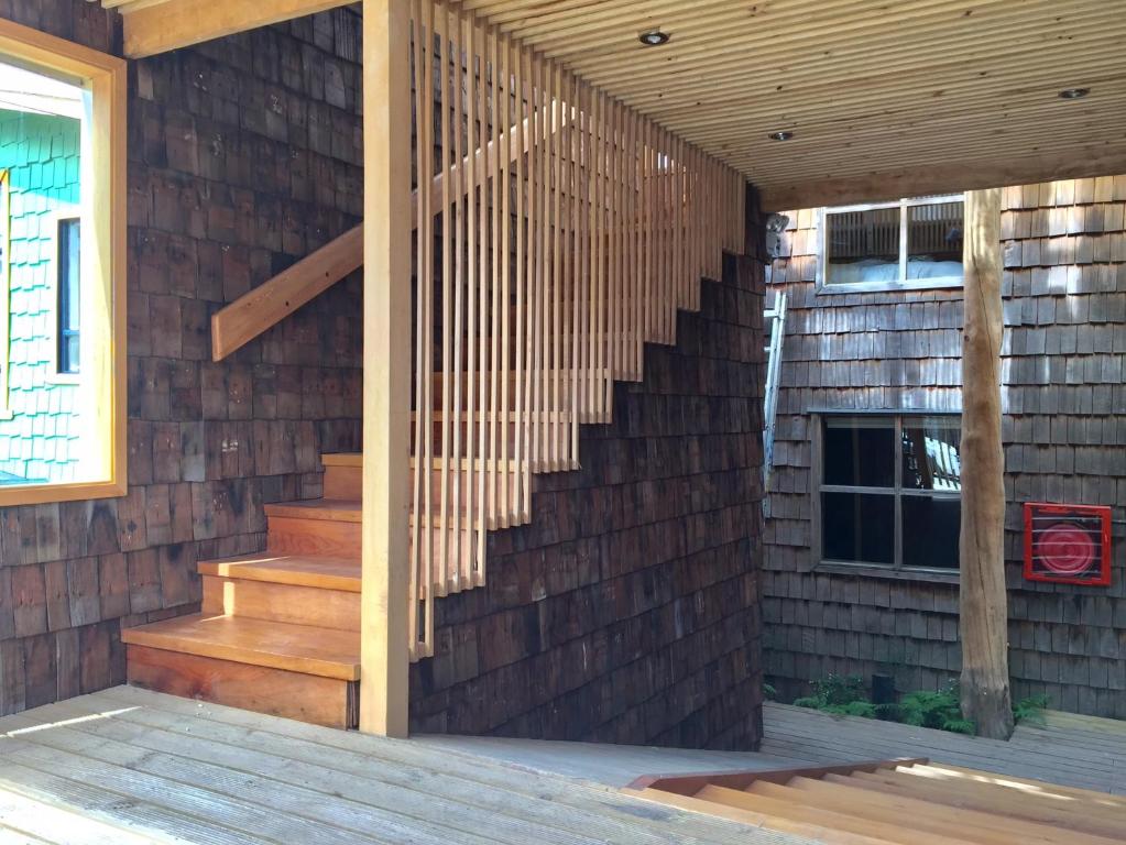 a wooden staircase in a building with a brick wall at Palafito Azul Apart Hotel in Castro