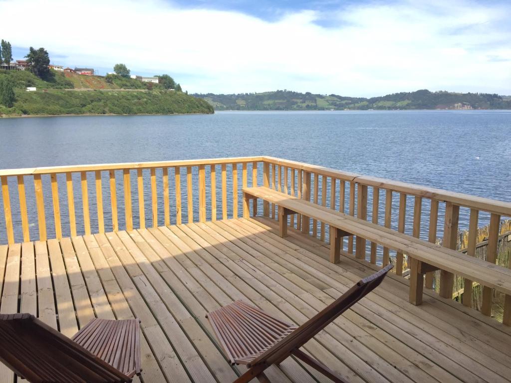 a deck with two chairs and a bench on the water at Palafito Azul Apart Hotel in Castro