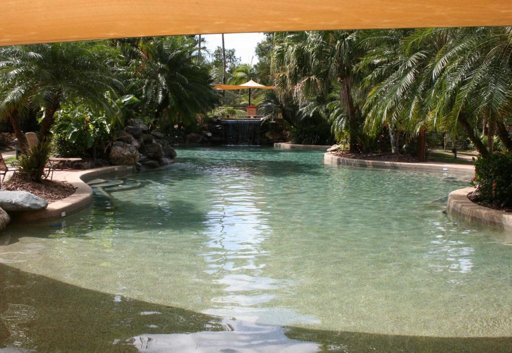 a swimming pool in a resort with palm trees at Cairns Golf Course Apartment in Cairns