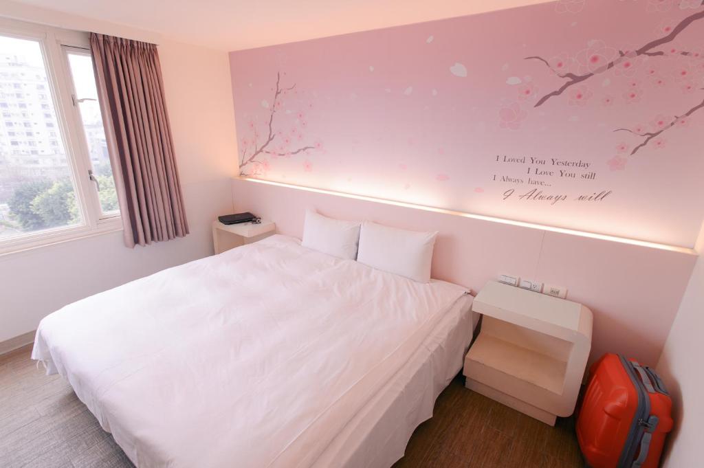 a bedroom with a white bed and a sign on the wall at Kiwi Express Hotel - Zhong Zheng Branch in Taichung