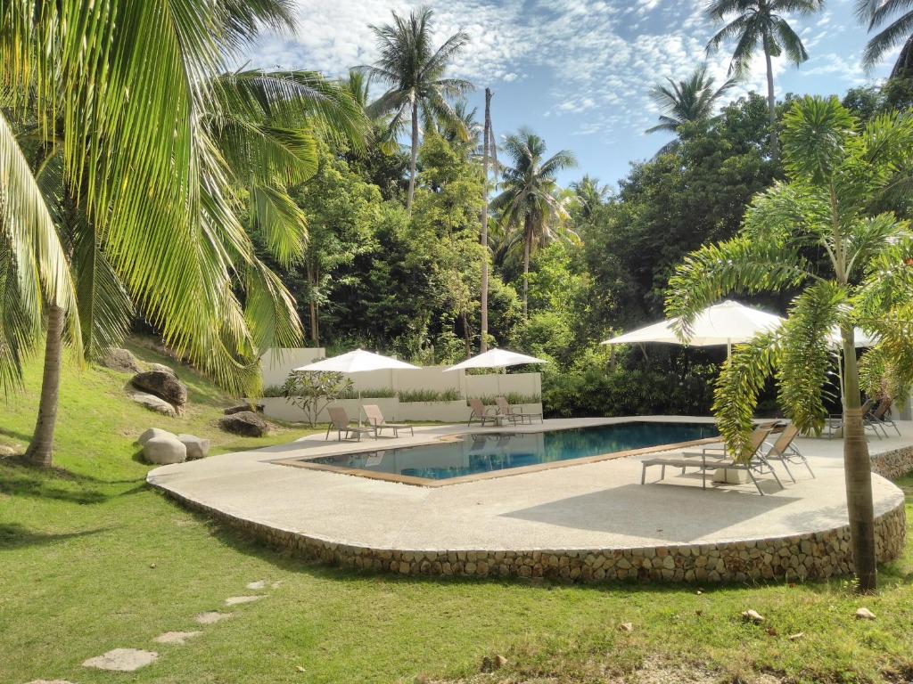 una piscina con sillas y sombrillas en un patio en Woodlawn Villas Resort, en Ko Tao
