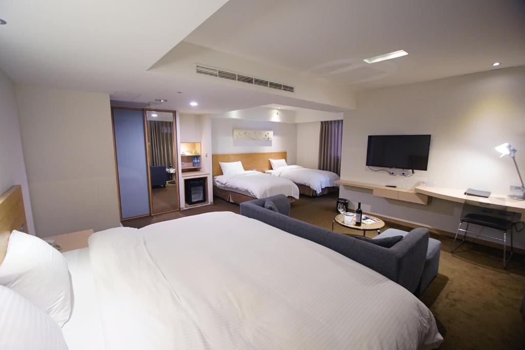 a hotel room with two beds and a flat screen tv at Beacon Hotel in Taichung