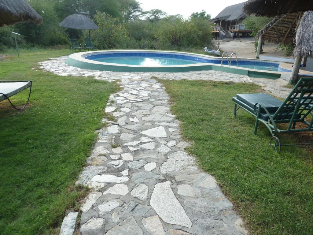 a stone path leading to a swimming pool with a bench at Roika Tarangire Tented Lodge in Kwa Kuchinia