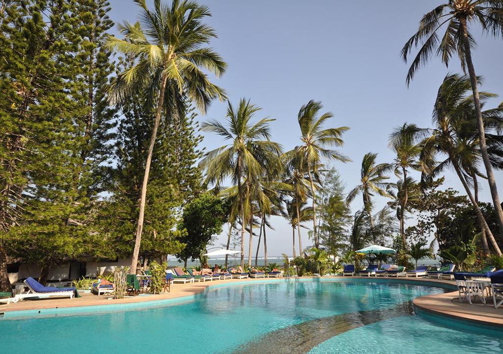 a large swimming pool with palm trees and chairs at Kilifi Bay Beach Resort in Kilifi