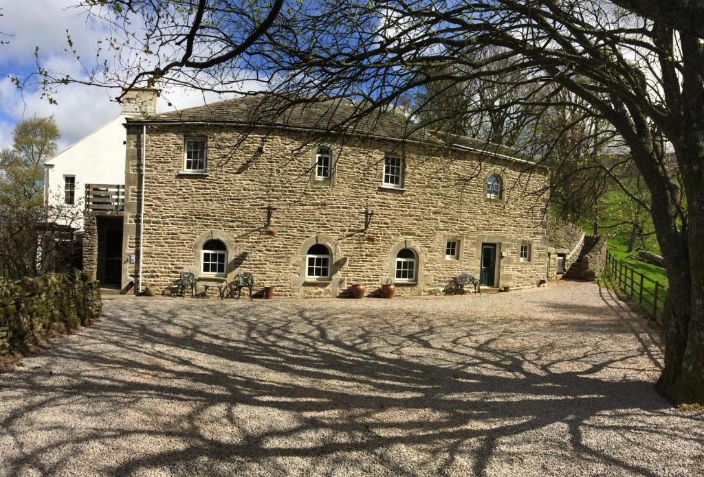 an old stone house with a tree in front of it at Elysian Fields @ Ing Hill Lodge in Outhgill