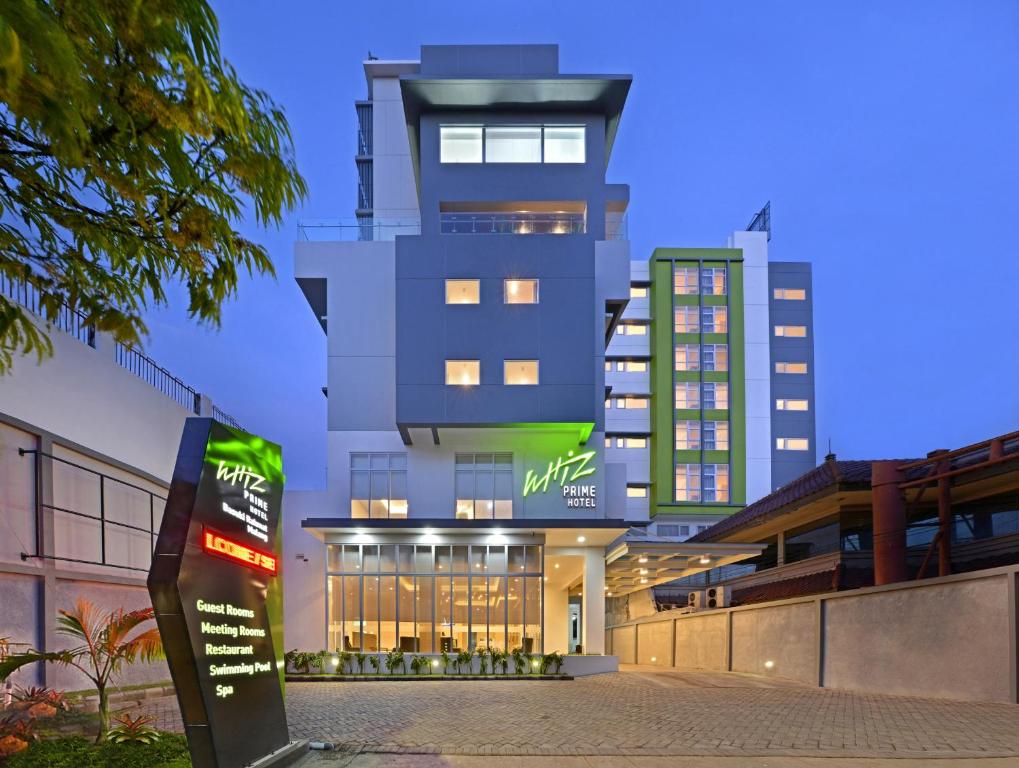 a tall building with a sign in front of it at Whiz Prime Hotel Basuki Rahmat Malang in Malang