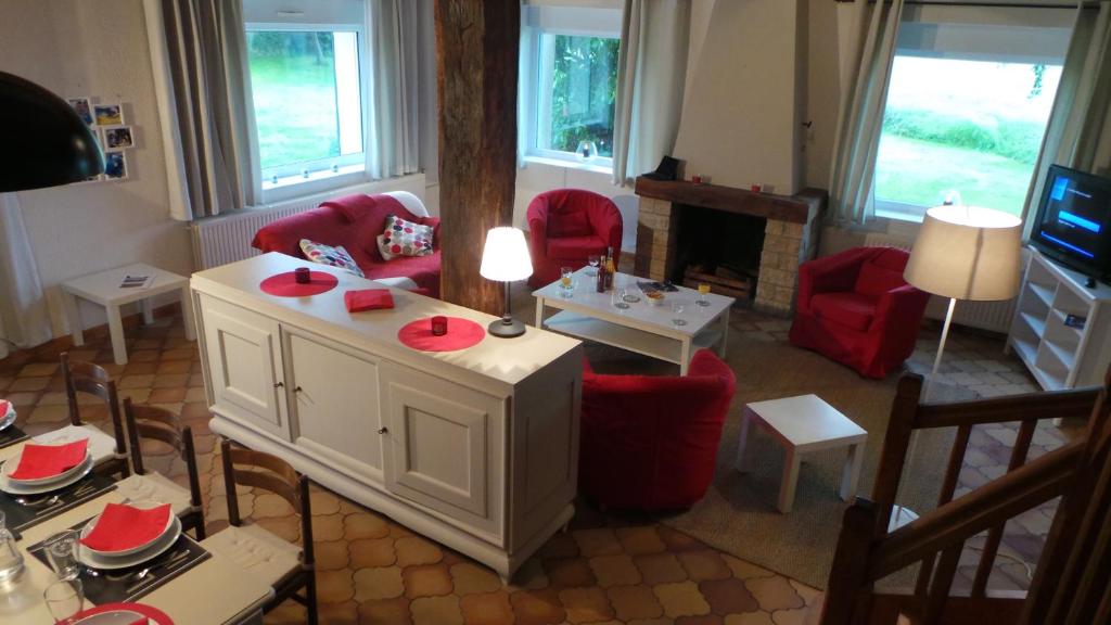un salon avec des chaises rouges et une cheminée dans l'établissement Gite le Courbat, à Le Liège